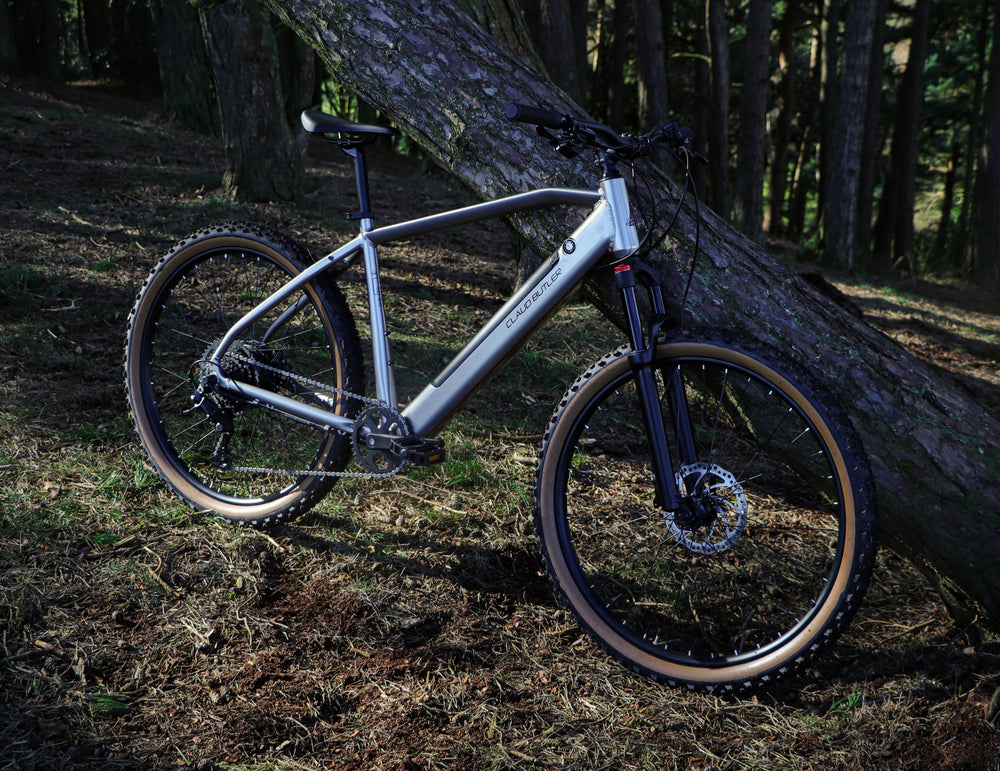Claud Butler Ridge 2.0 Electric Mountain Bike - leaning on a fallen tree in the woods — view 13