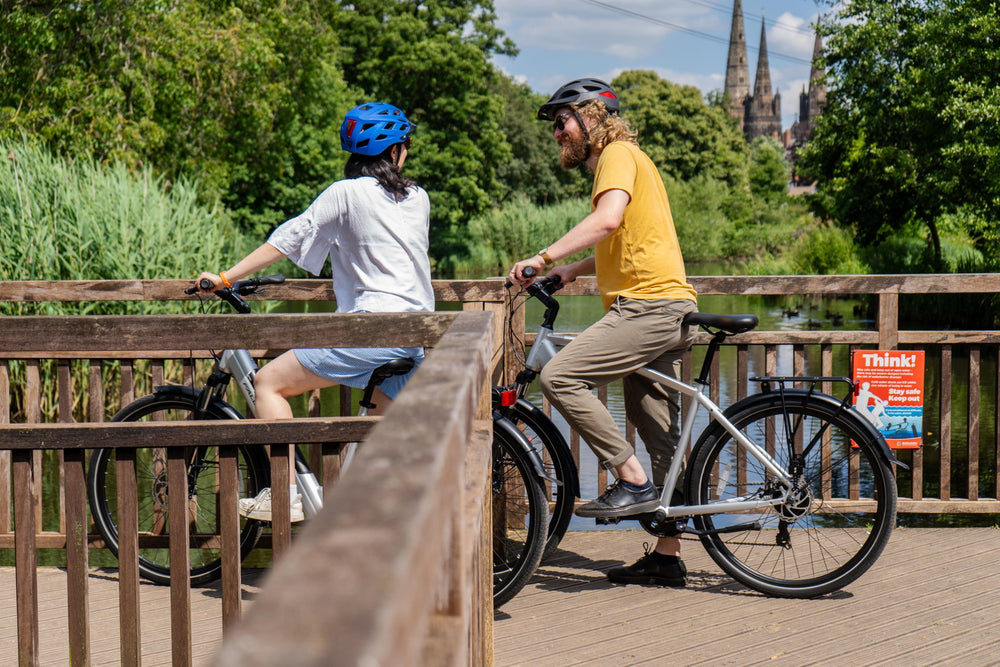 Falcon Horizon electric hybrid bikes - riders pausing on a footbridge — view 13